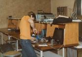 Color photograph of an individual using a screwdriver on a piece of equipment.